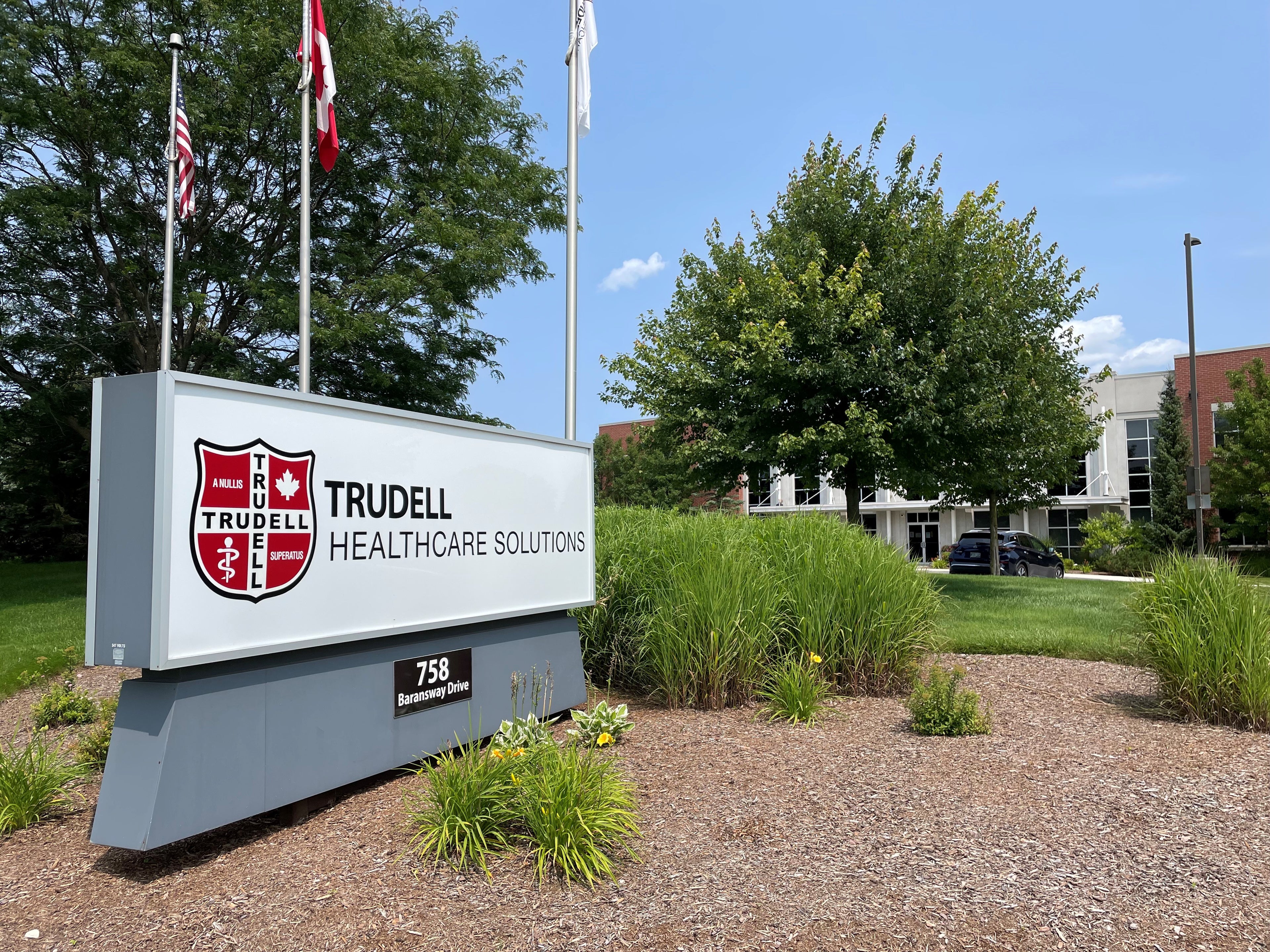 Trudell Healthcare Solutions sign with flags in a park-like setting